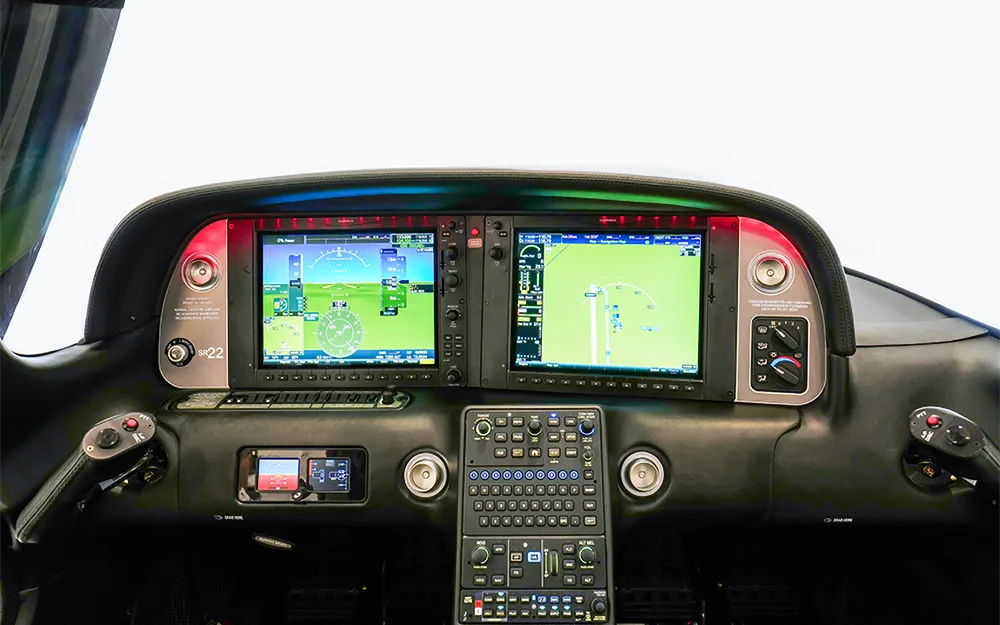 The modern glass cockpit of a Cirrus SR22 aircraft, featuring two large display screens and a central control panel.