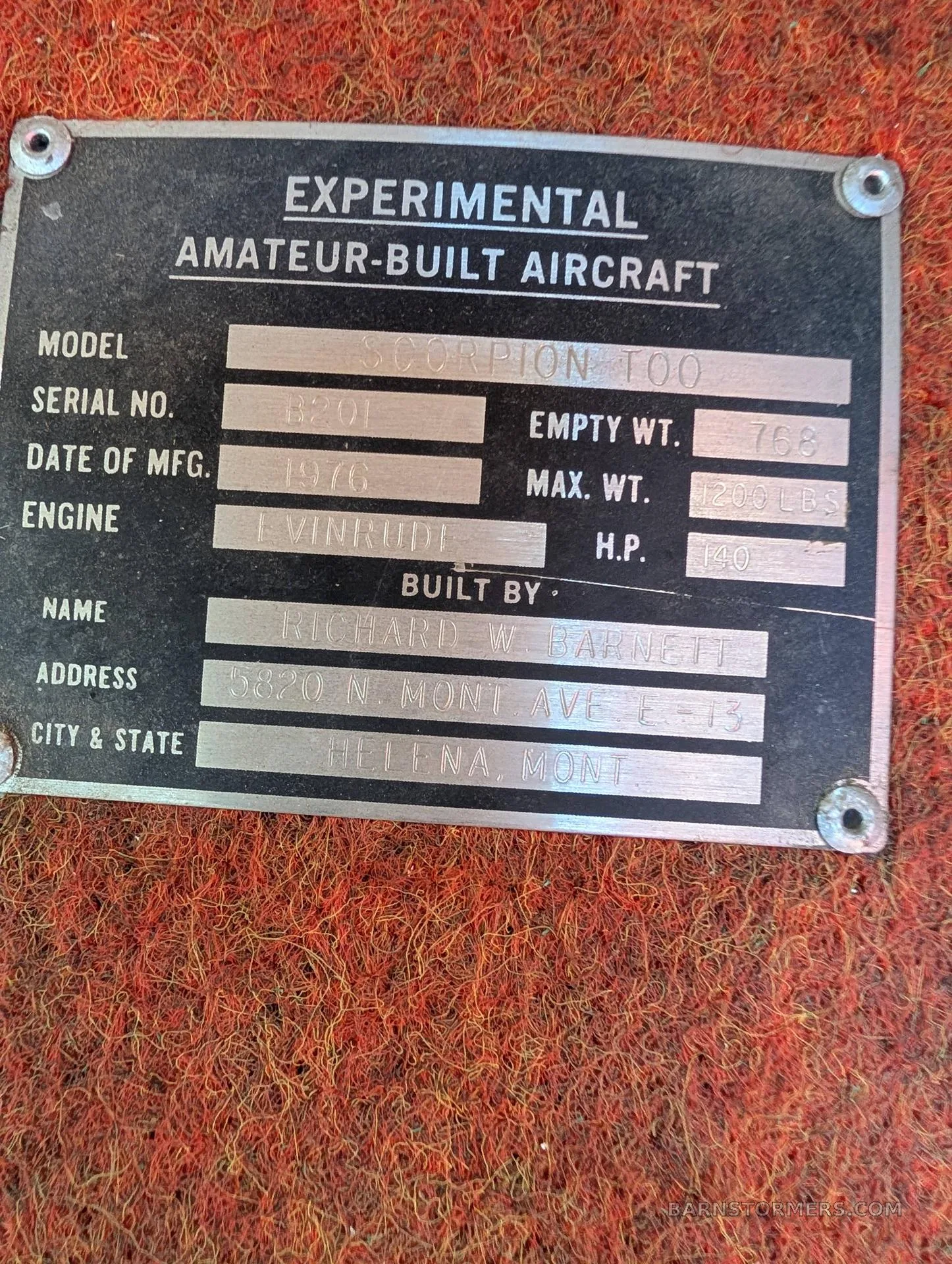 A close-up of a black metal data plate for an "EXPERIMENTAL AMATEUR-BUILT AIRCRAFT" showing "SCORPION TOO" model and builder details.