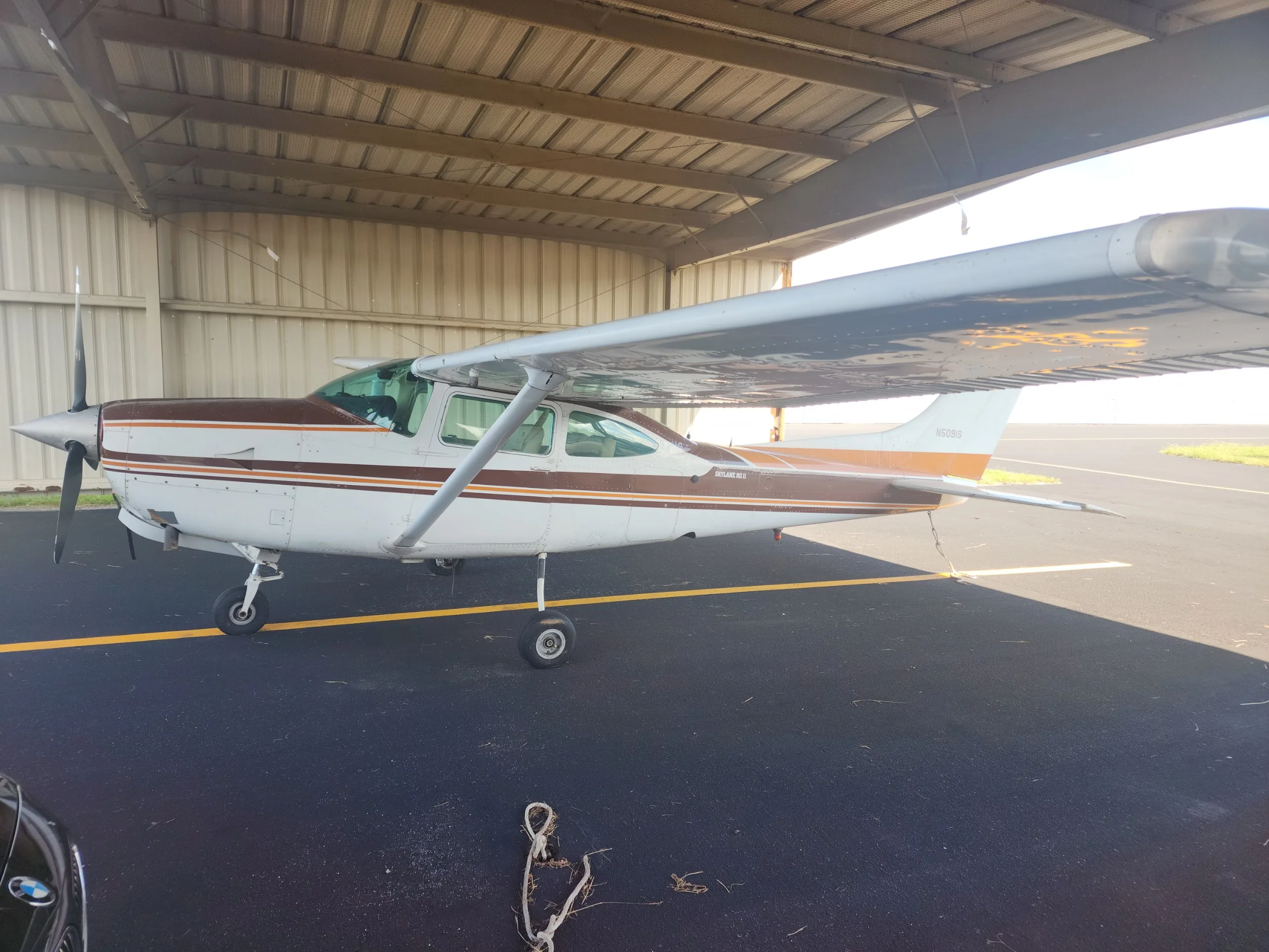 A white and brown Cessna Skylane RG II (N5019S) parked in a hangar, viewed from the side.