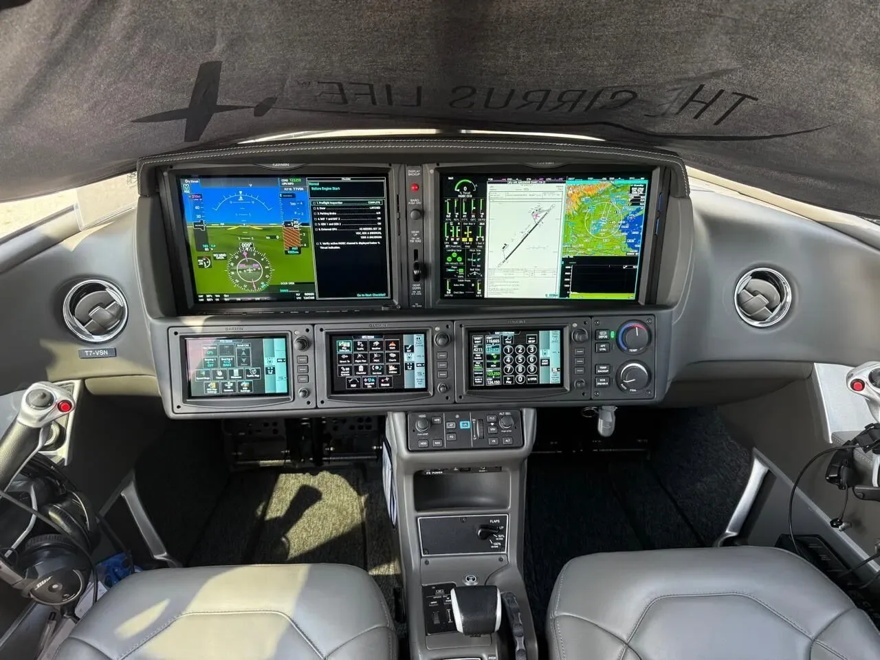 The modern glass cockpit of a Cirrus Vision Jet with multiple display screens and controls.