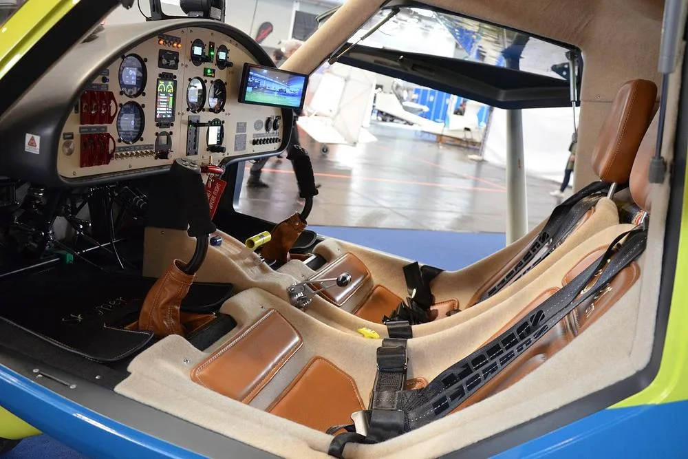 The interior cabin of a Skyper GT9 aircraft with tan seats and a visible instrument panel.