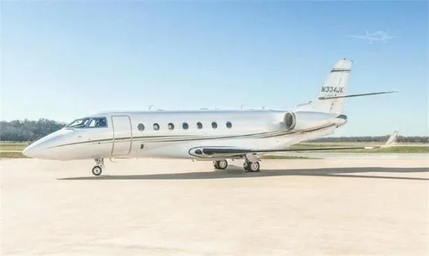 A white business jet, likely a Hawker 800XP with registration N334JK, parked on an airfield under a clear blue sky.