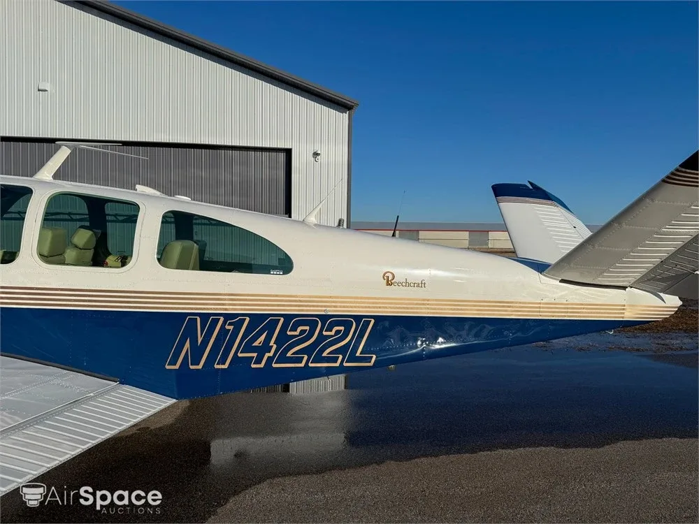 Close-up of the tail section of the Beechcraft Bonanza, showing the N1422L registration and blue and white paint scheme.