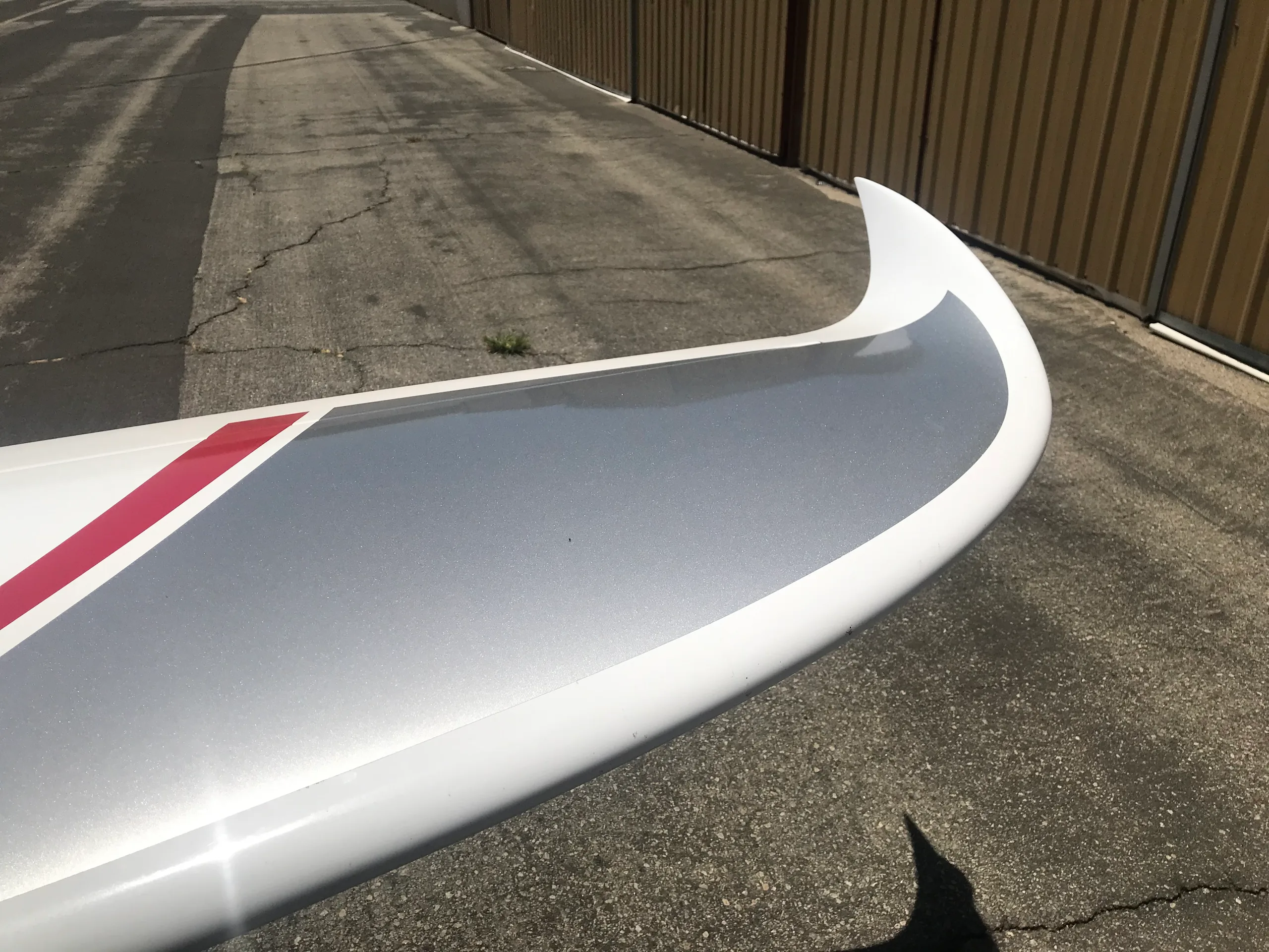 A close-up of the white wingtip of a Pipistrel Panthera aircraft, featuring red and silver paint accents.