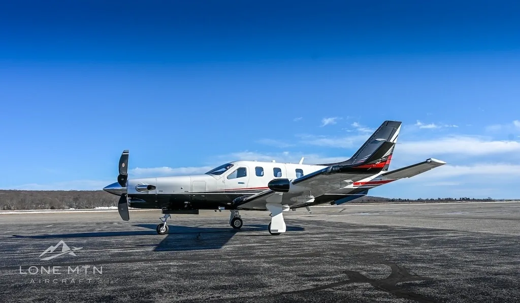 A TBM 940 aircraft, registration N944EA, parked on a runway or large tarmac under a clear blue sky.