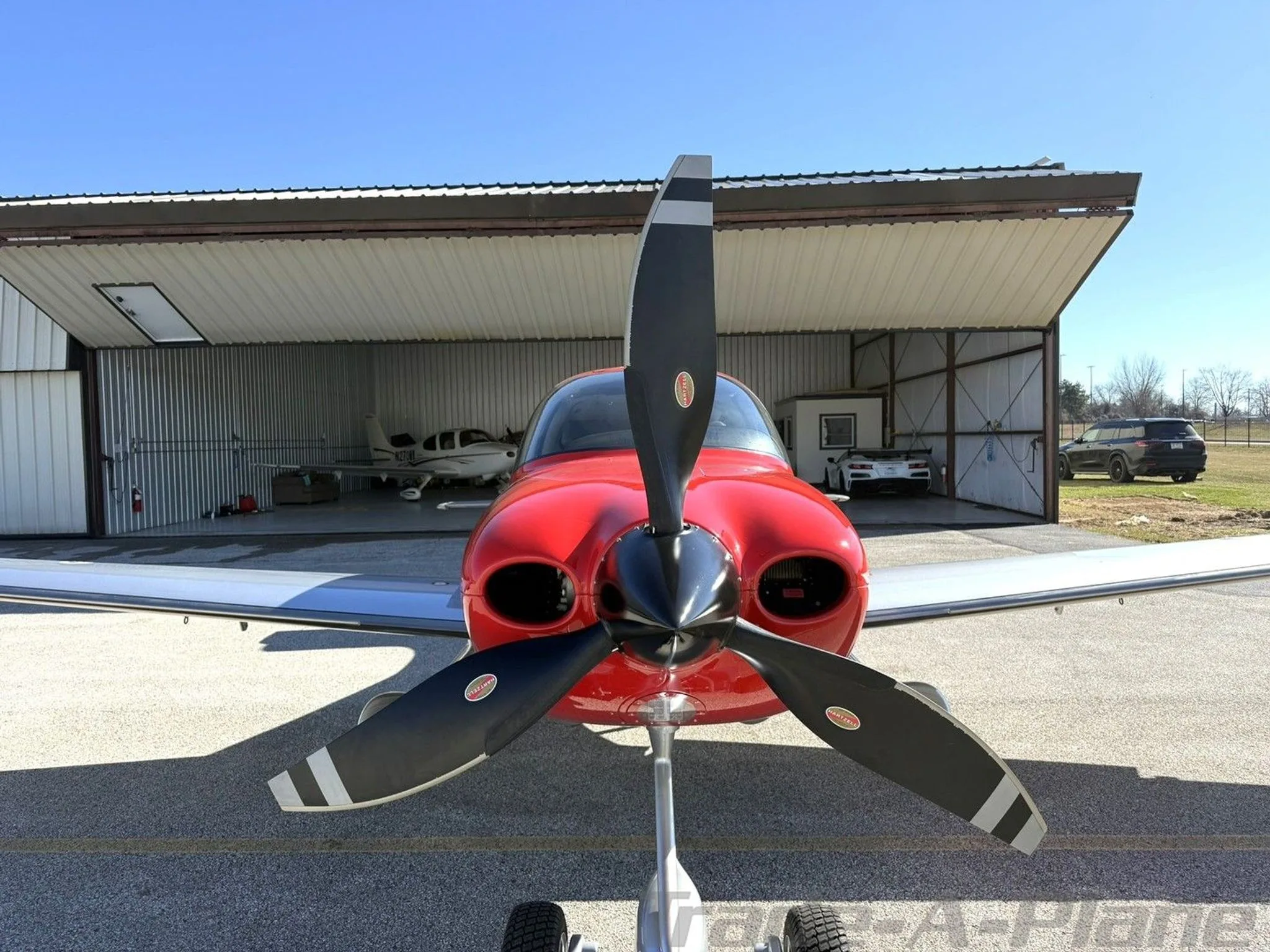 A head-on view of the red and silver Cirrus SR22T aircraft, N776BW, with its propeller centered.