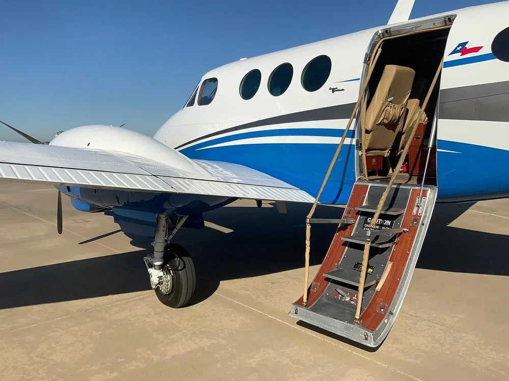 A close-up view of the open passenger door and integrated airstair of the white and blue turboprop aircraft.