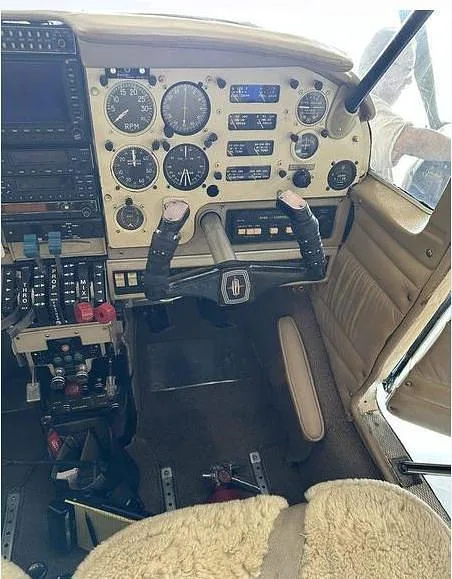 The aircraft's cockpit features a beige instrument panel with analog gauges and a control yoke.