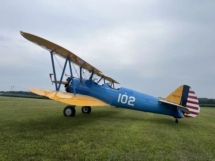 A blue and yellow biplane parked on a grassy field.