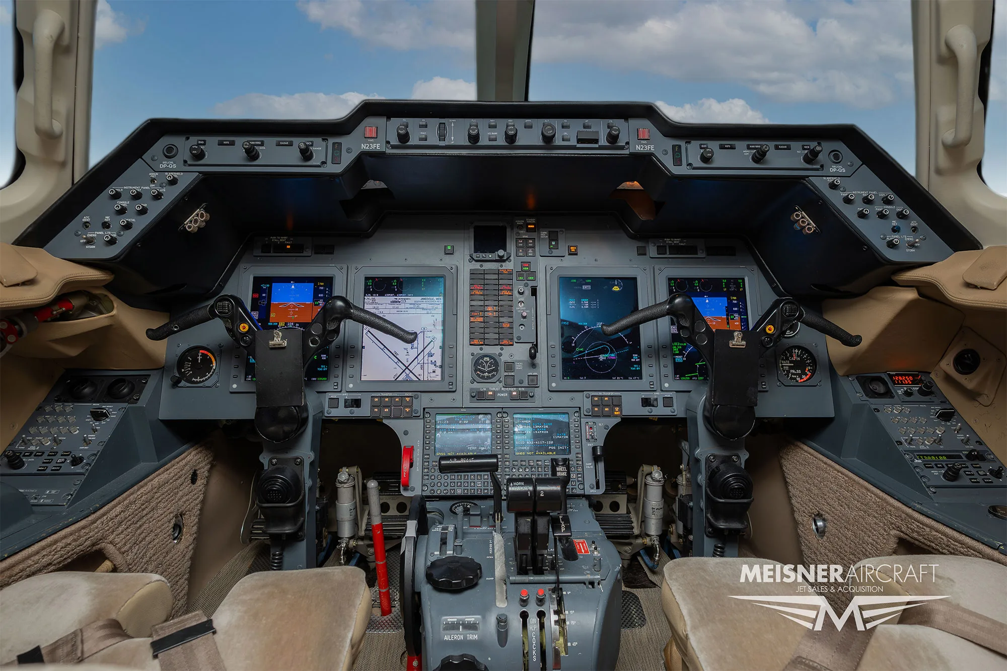 The cockpit of a business jet, showing multiple digital displays and control panels.