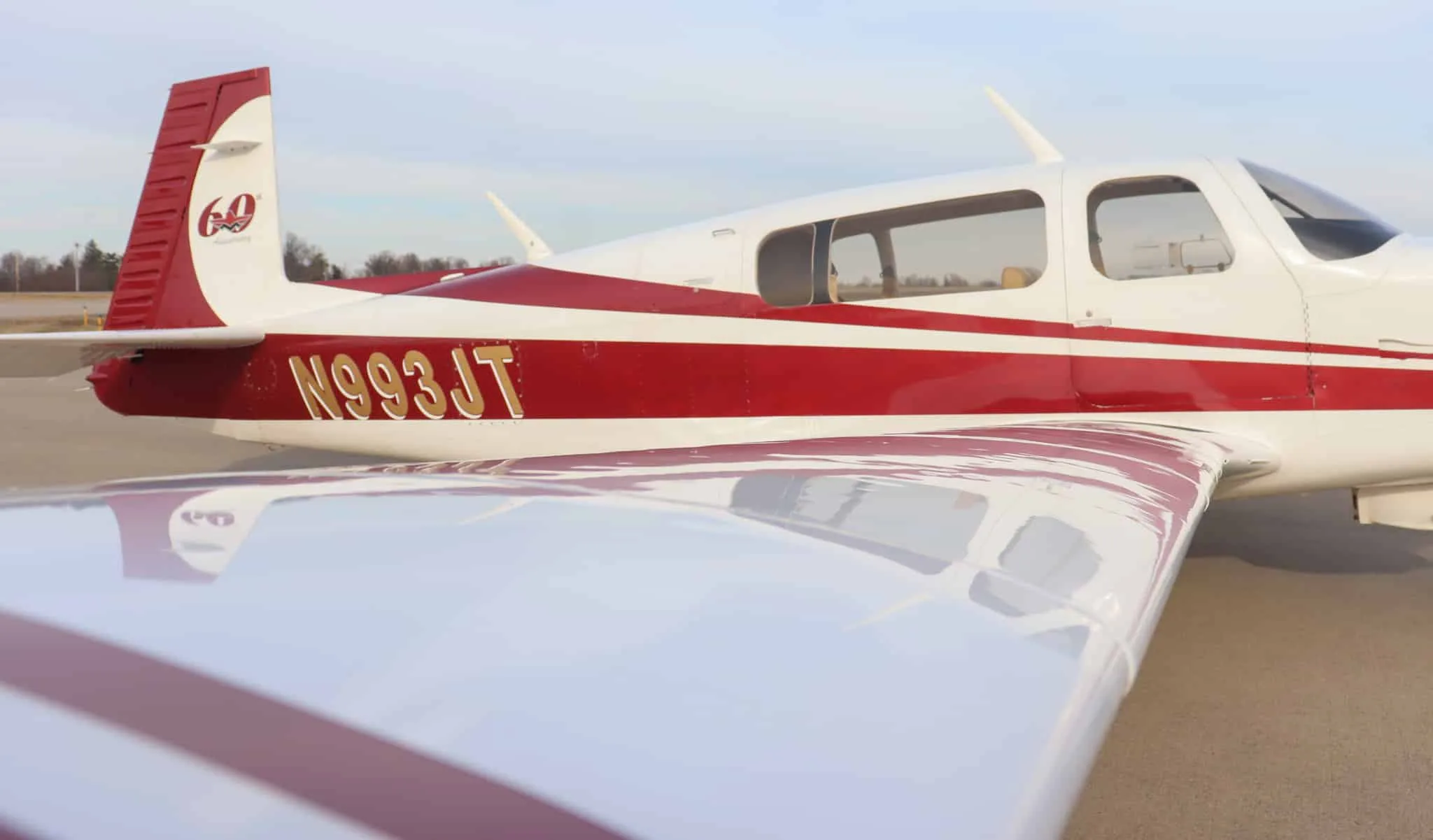 Close-up of the tail and wing of a white and red aircraft, N993JT, showing the 60th Anniversary logo.