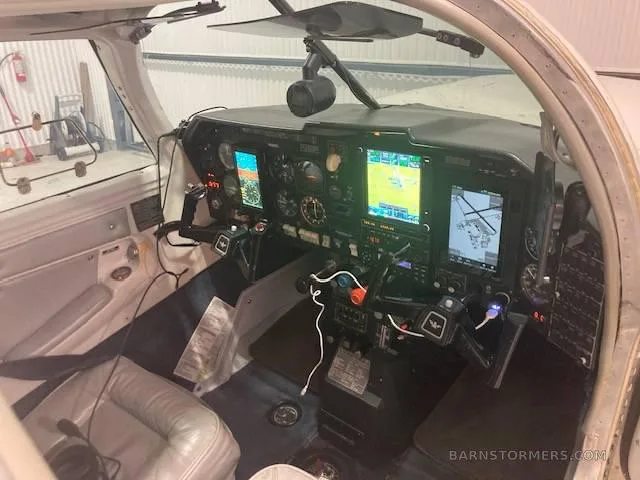 The cockpit of a small aircraft, showing the instrument panel with multiple digital displays and yokes.
