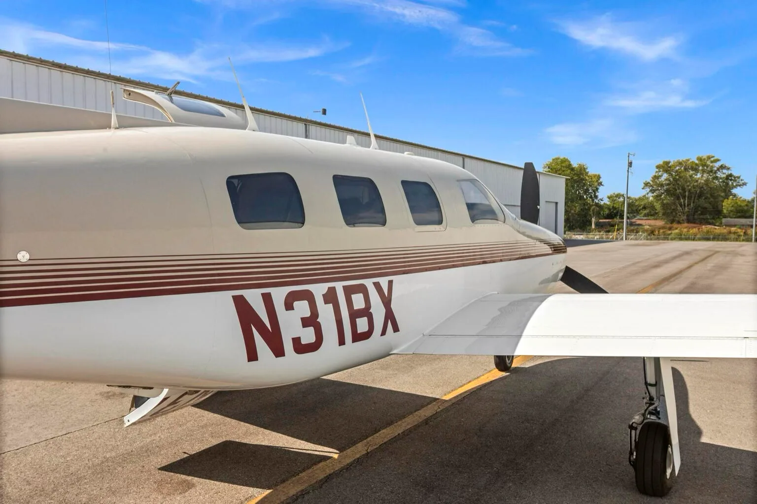 A close-up of the Piper Malibu N31BX fuselage, showing the registration number and red stripe details.