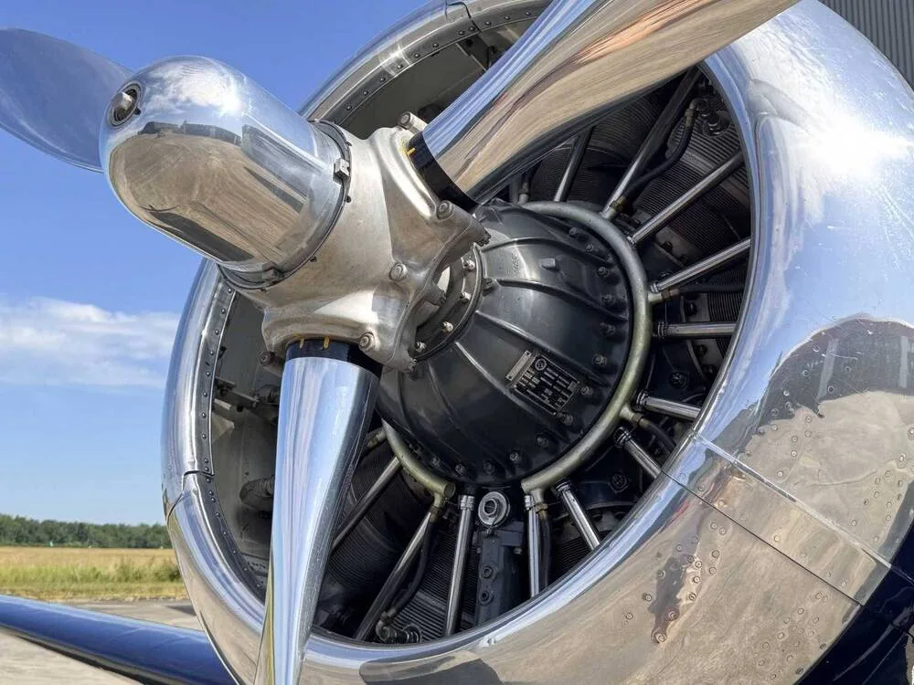 A close-up view of the polished chrome propeller and radial engine of a dark blue North American T-6 Texan aircraft.