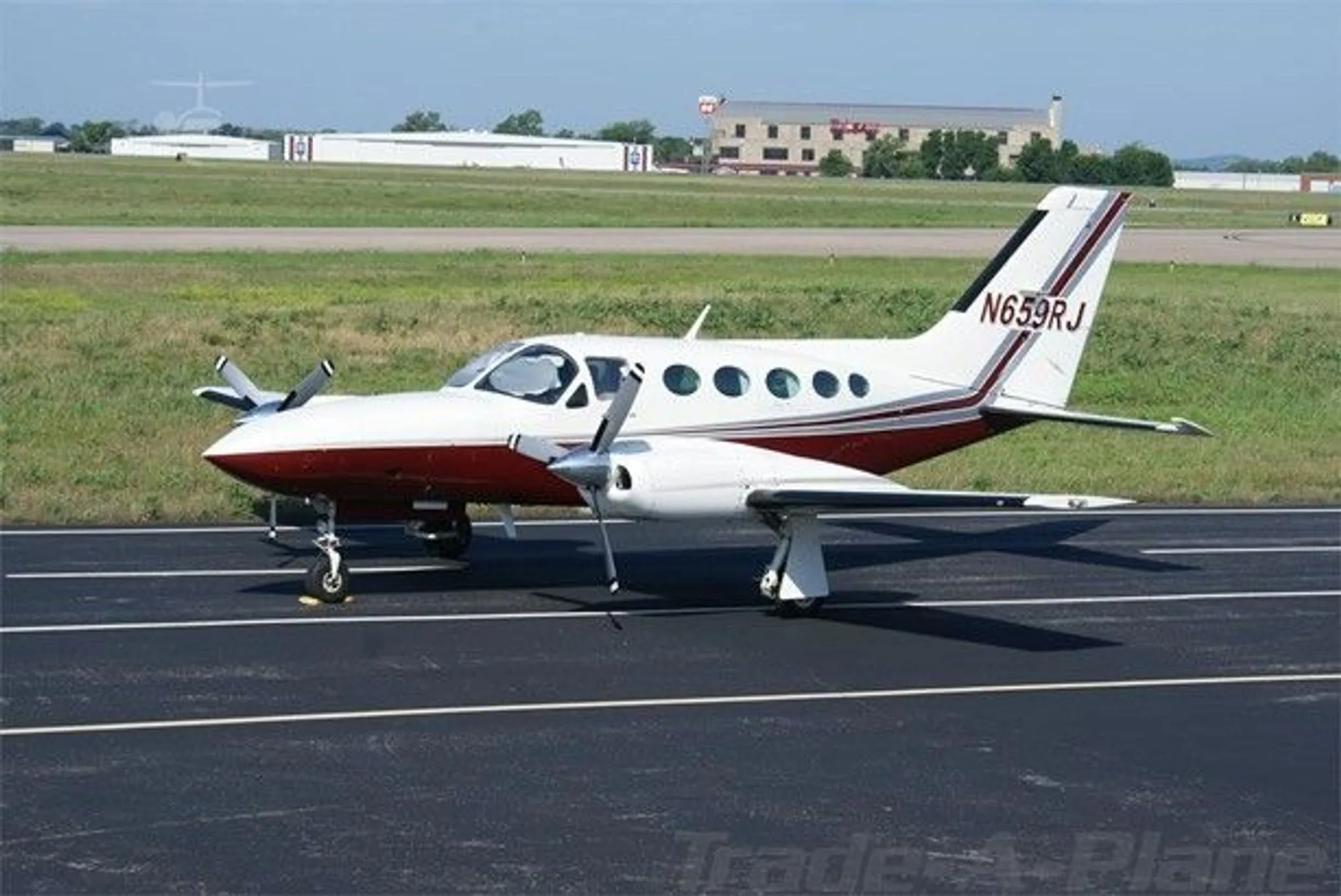 A white and maroon twin-engine Cessna 421C Golden Eagle aircraft (N659RJ) parked on an asphalt runway with buildings in the background.