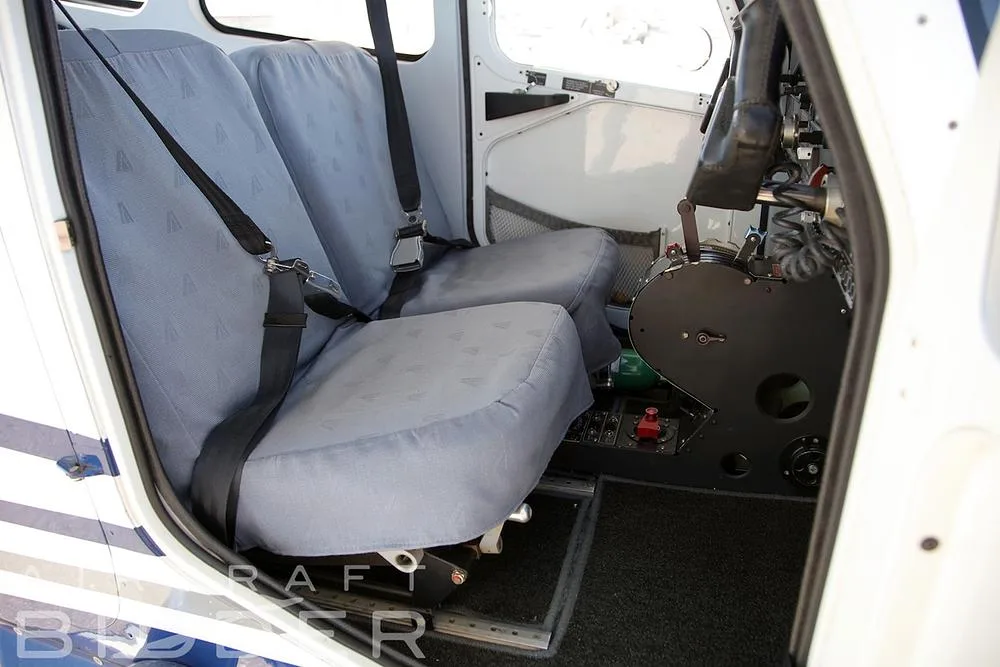 The light gray fabric seats in the cabin of the N121VA Tecnam P2010 aircraft, viewed from the open door.
