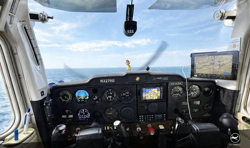 The cockpit of a Cessna 172 showing the instrument panel with a view of the ocean through the windshield.