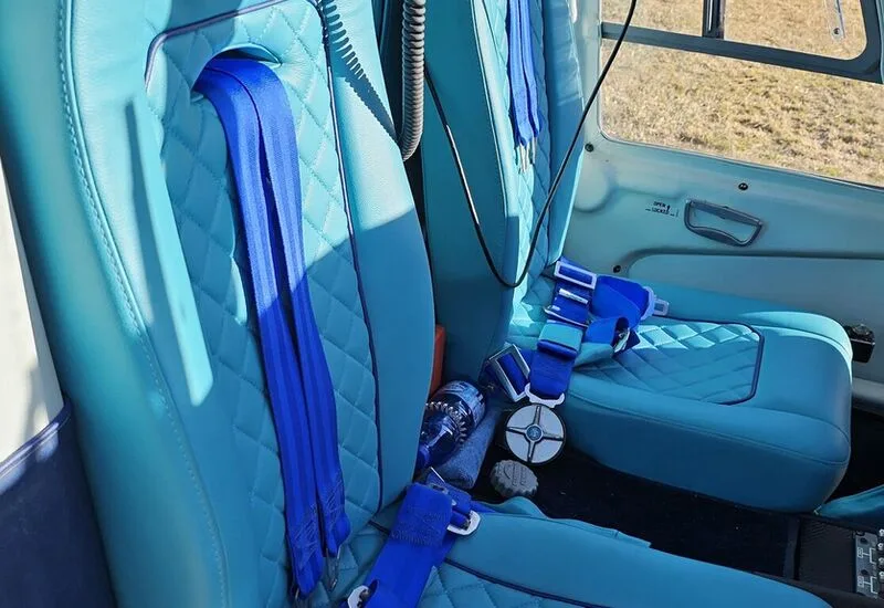 Close-up of the light blue leather seats with blue seatbelts inside the helicopter.