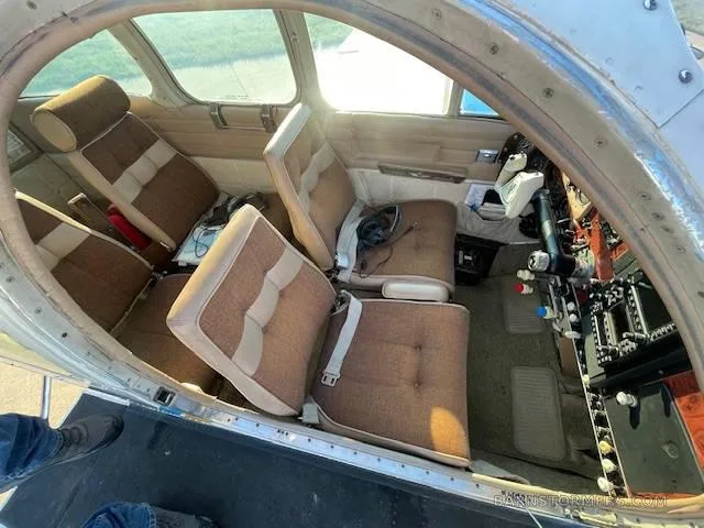 The interior cabin of a small aircraft features brown and beige striped seats, viewed from the open door.