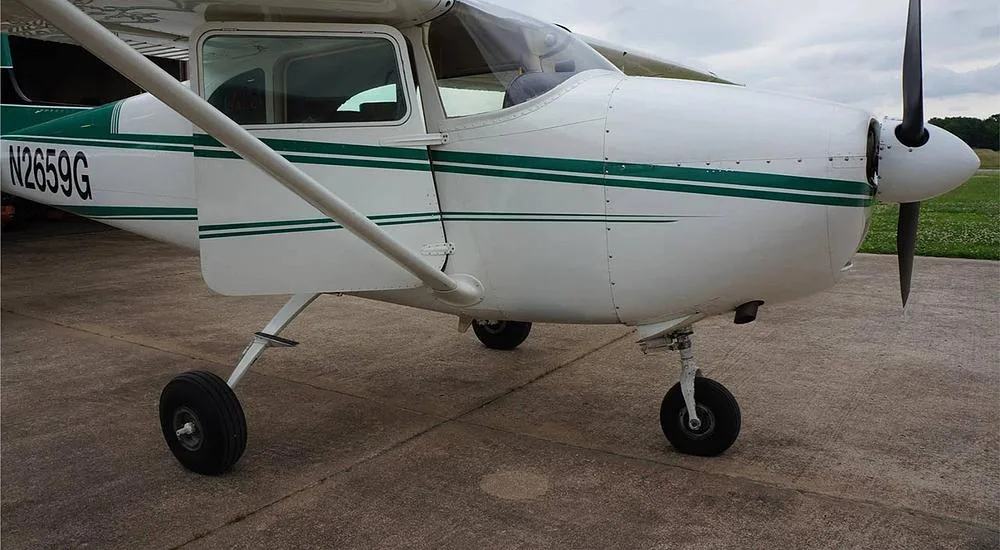 A close-up side view of the front fuselage and propeller of a white aircraft with green stripes, registration N2659G.