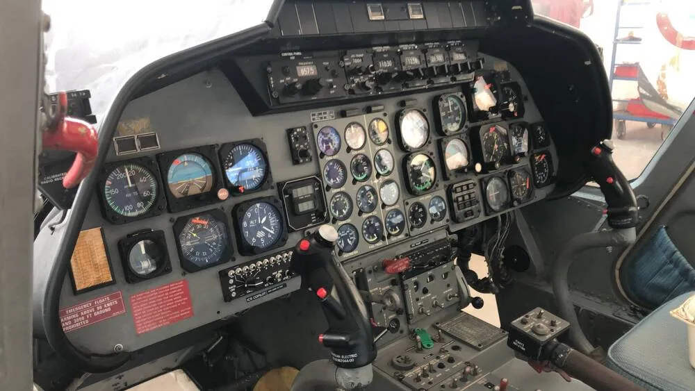 The detailed instrument panel of a helicopter cockpit, featuring numerous analog gauges and controls.