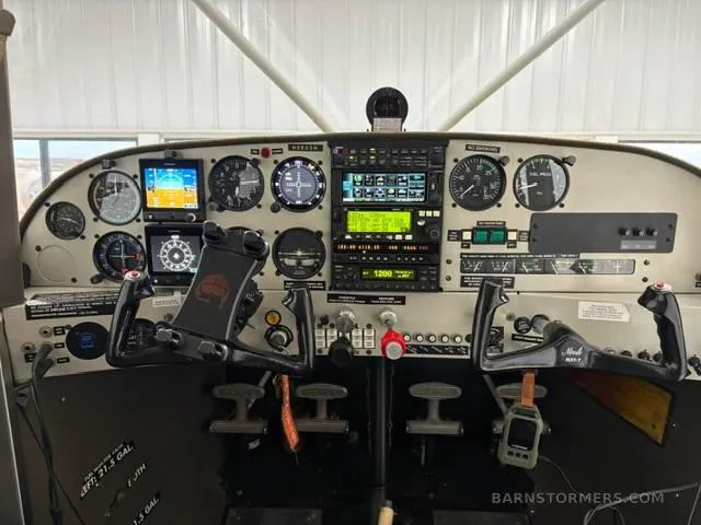 The cockpit of a Maule M-7-235B aircraft, showing the instrument panel with analog gauges and digital displays, and two control yokes.