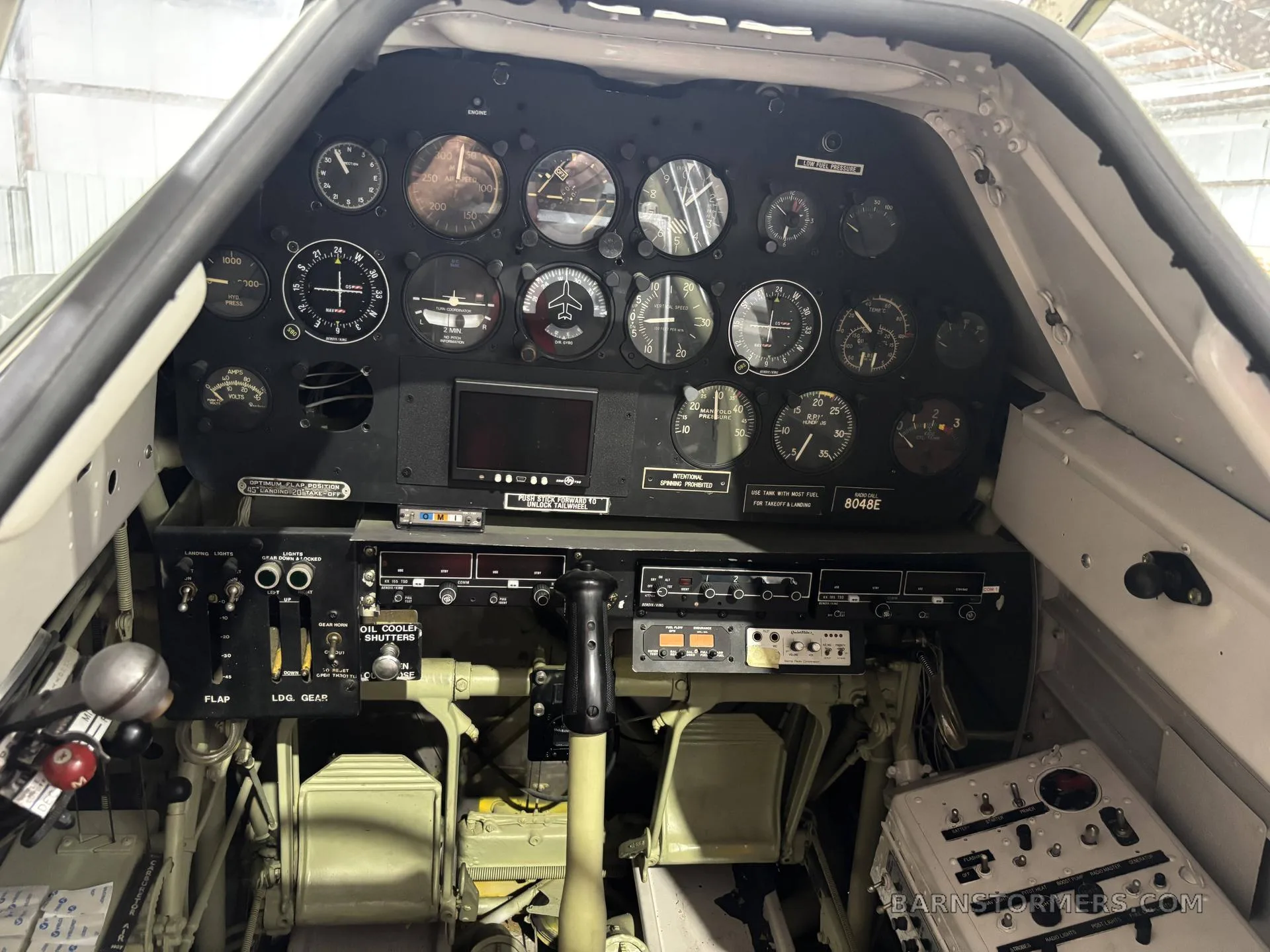 The cockpit of a T-6G Texan aircraft, showing the instrument panel with numerous gauges and controls.