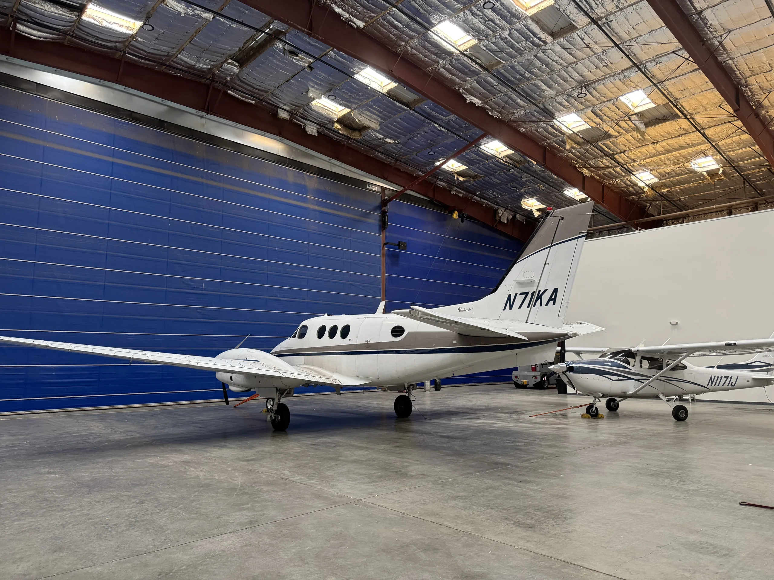 Side view of N71KA King Air turboprop aircraft parked in a hangar.