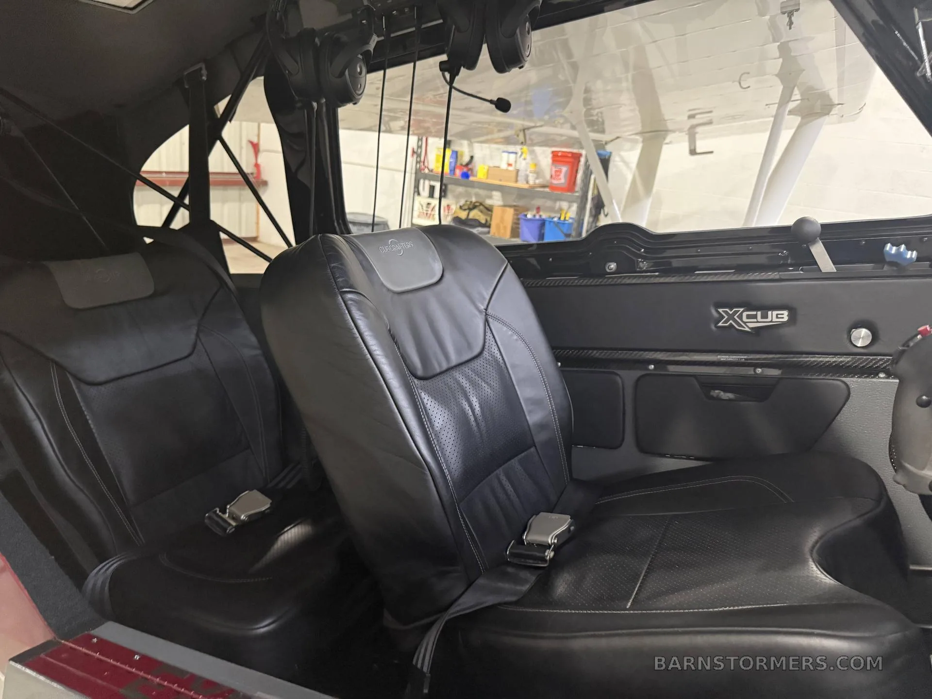 The black leather interior of an X-Cub aircraft, showing two front seats and the cabin area.