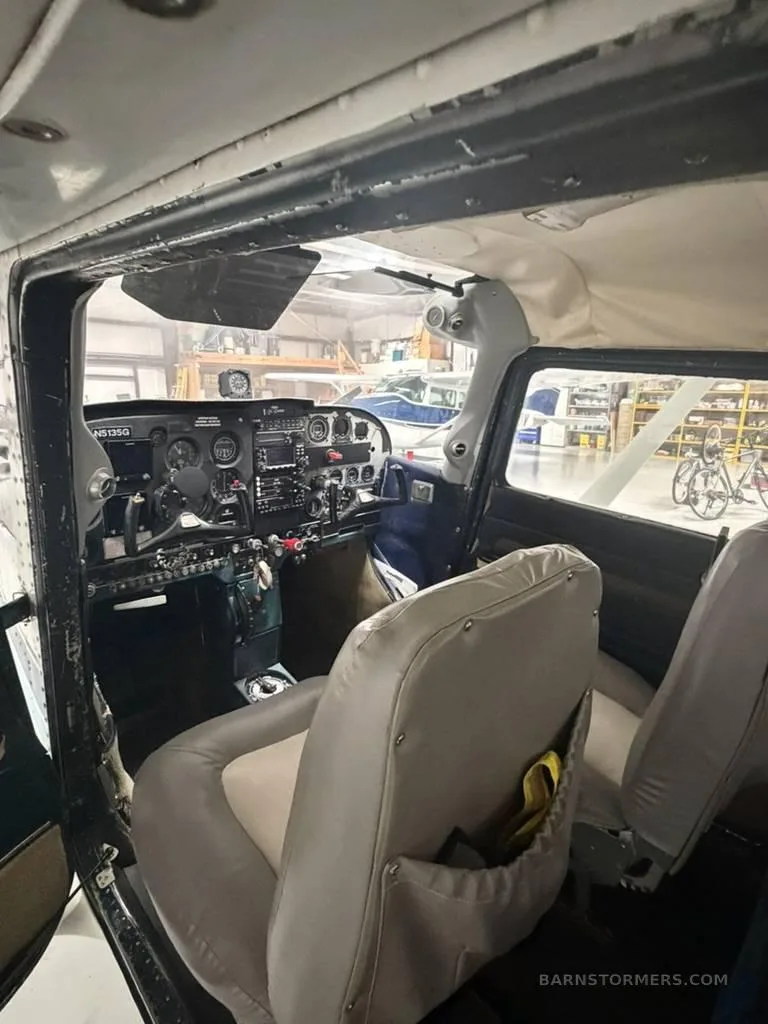 The interior cabin of a Cessna 172, showing the front seats and a view of the cockpit from the side.