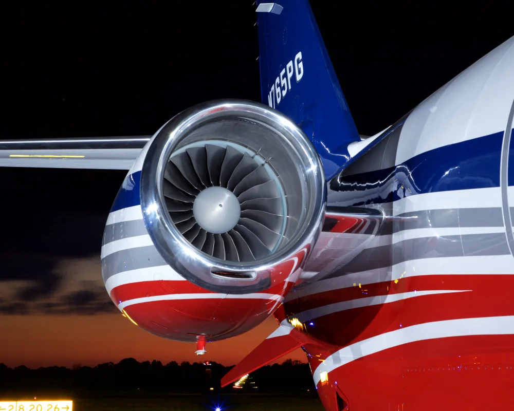 A close-up view of the jet engine and tail (N765PG) of a private aircraft at night.