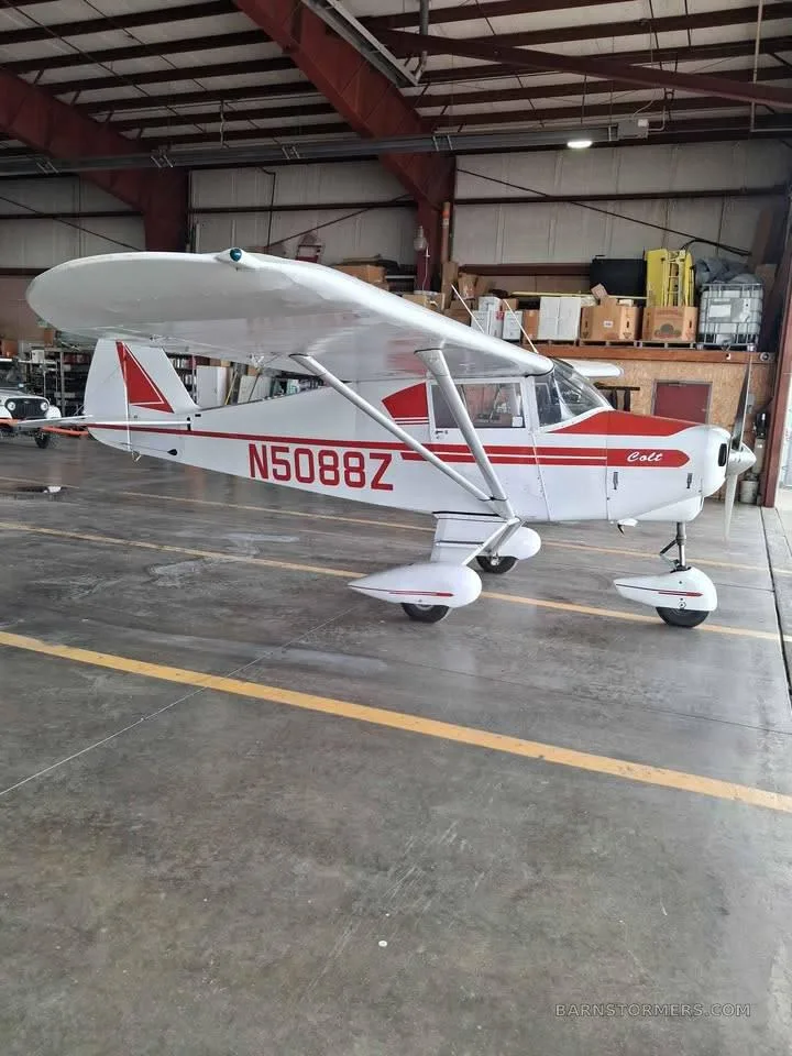 A white Piper Colt aircraft with red stripes and registration N5088Z is parked inside a hangar.
