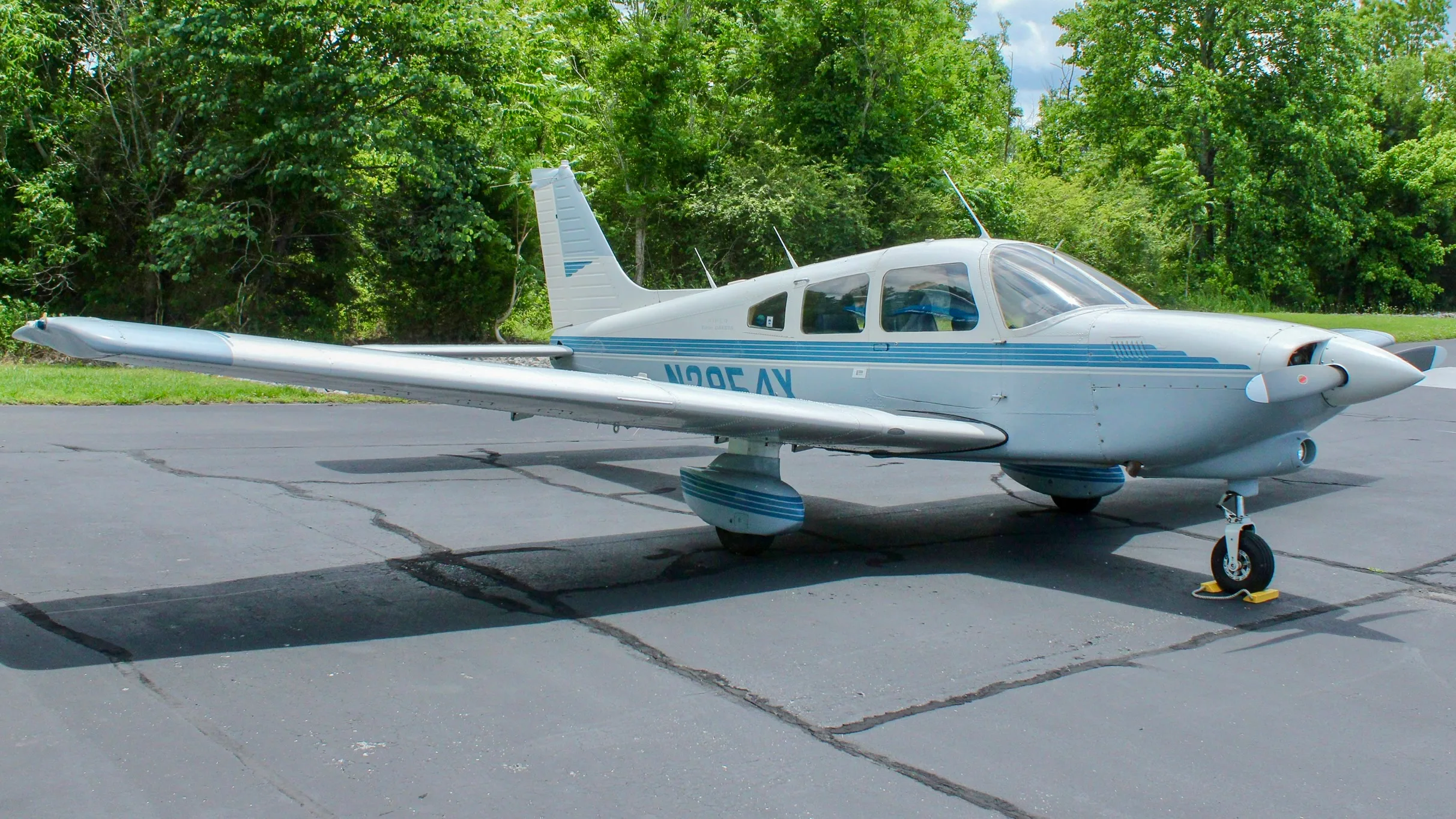 A three-quarter front view of a white and blue Piper Cherokee aircraft, registration N2854X, parked on an asphalt ramp.