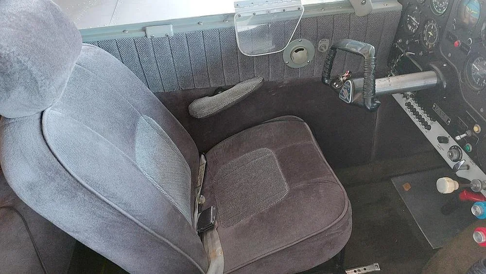 The gray fabric pilot's seat and side panel with controls inside an aircraft.