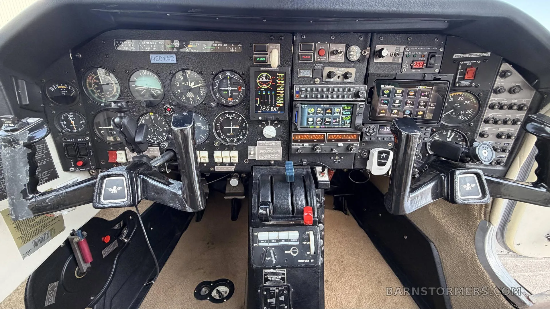 A detailed view of an aircraft cockpit with analog gauges, modern avionics, and dual yokes.