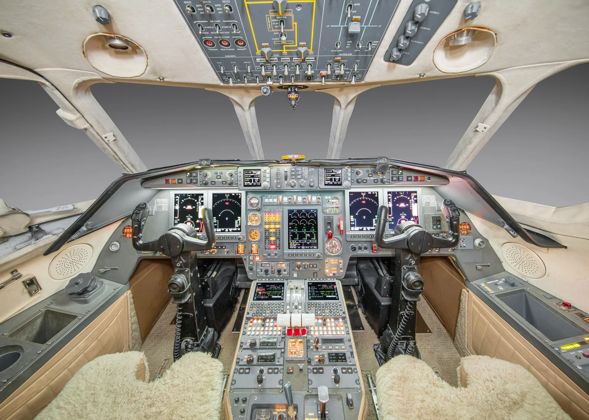 A wide view of a modern aircraft cockpit with multiple digital displays and control panels.