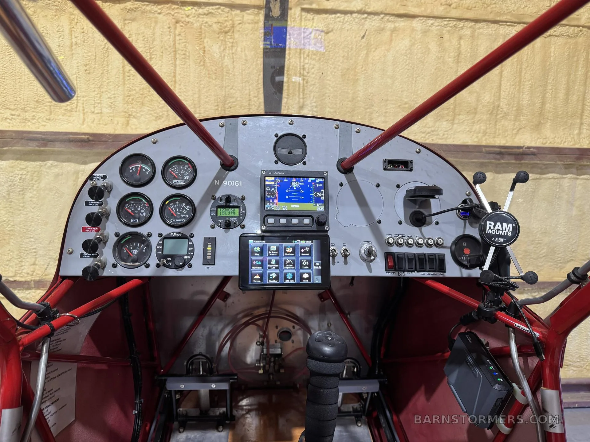 The cockpit of a light aircraft, featuring analog gauges, a central digital display, and a tablet mounted on the right.