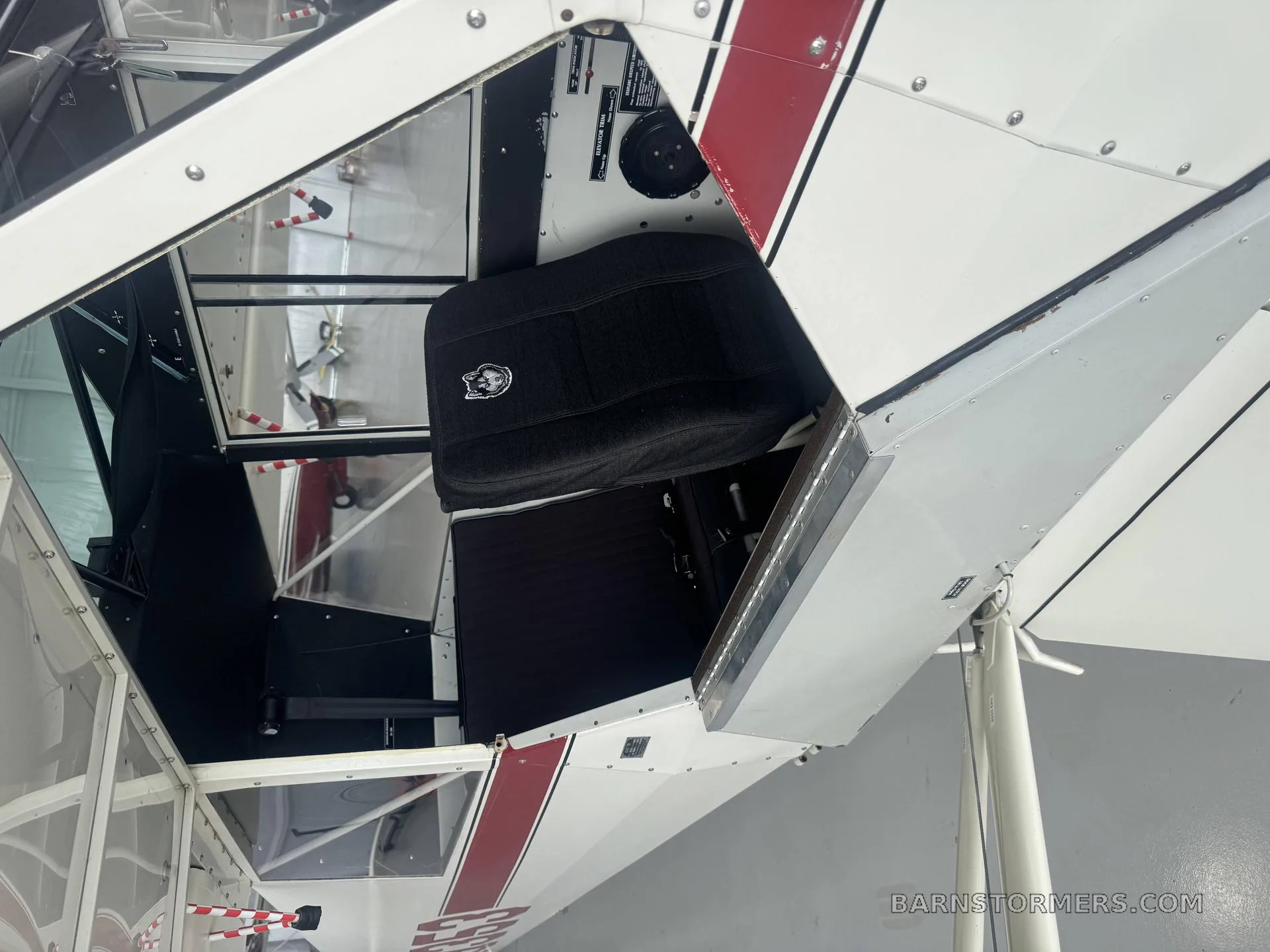 The interior cabin of the Aviat Husky A-1 shows black fabric seats and the aircraft's structure.