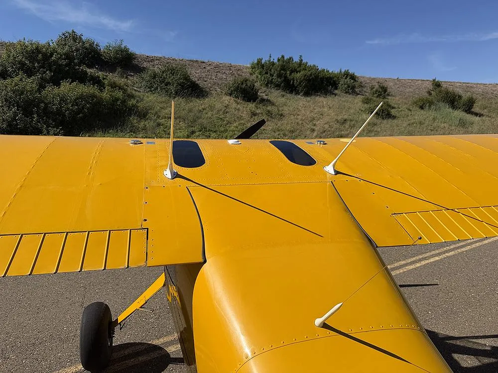 Overhead view of the yellow aircraft's wing and fuselage, showing antennas and the top surface details.