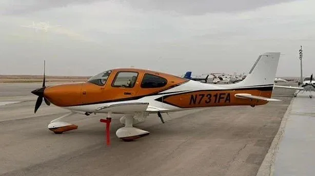 A Cirrus SR22 aircraft with an orange and white paint scheme, registration N731FA, parked on an airfield.