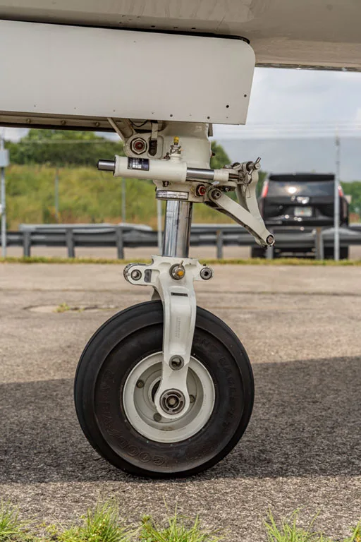 A close-up view of the main landing gear wheel and strut of an Embraer Phenom 100.