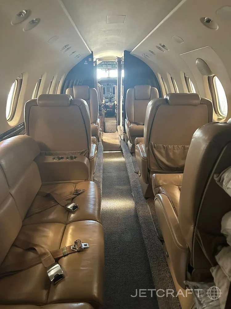A long view of a private jet's tan leather cabin interior looking towards the cockpit.