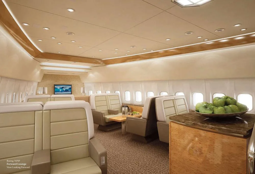 A rendering of a luxurious forward lounge area inside a Boeing 747SP, featuring light beige seating and a table with green apples.