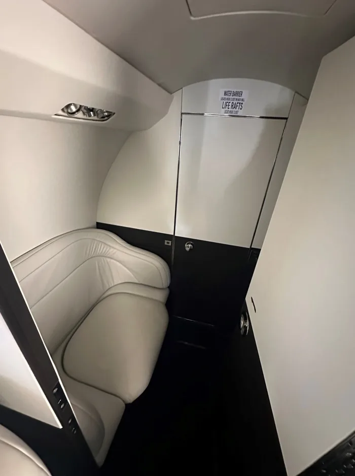 View of the aircraft's interior with a white leather seat and a door with a sign.