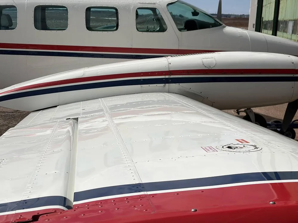 A close-up of the N303WJ aircraft's fuselage and wing, highlighting the red and blue stripe details.