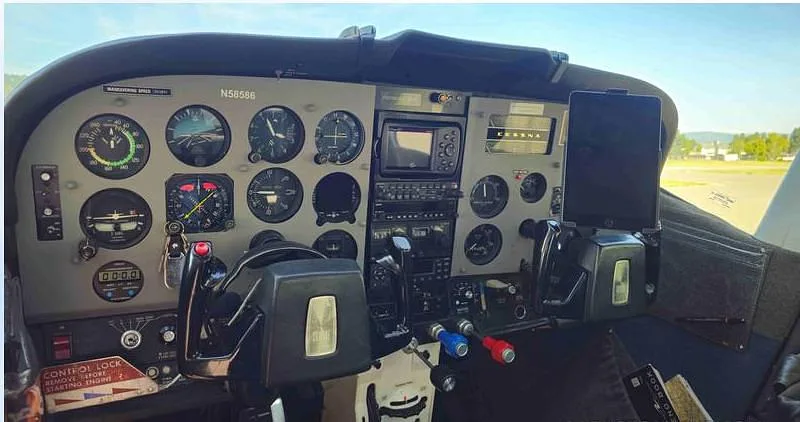 The cockpit of a Cessna aircraft, showing the instrument panel, yokes, and a mounted tablet.