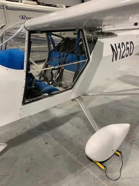The side view of a white Kitfox aircraft with registration N125D, showing the open door and blue interior.