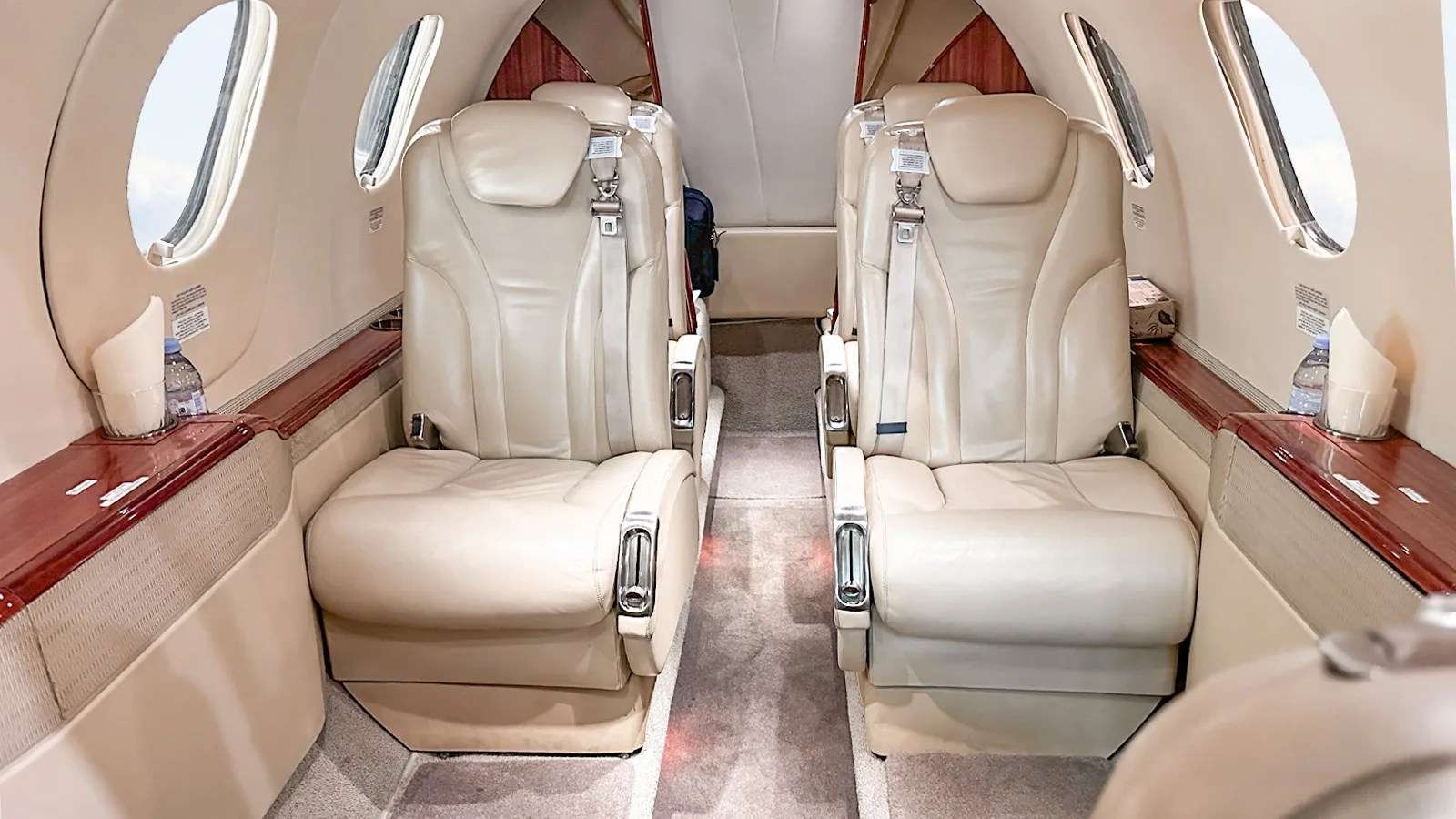 A view of the beige leather seats and wood trim in the private jet's cabin.