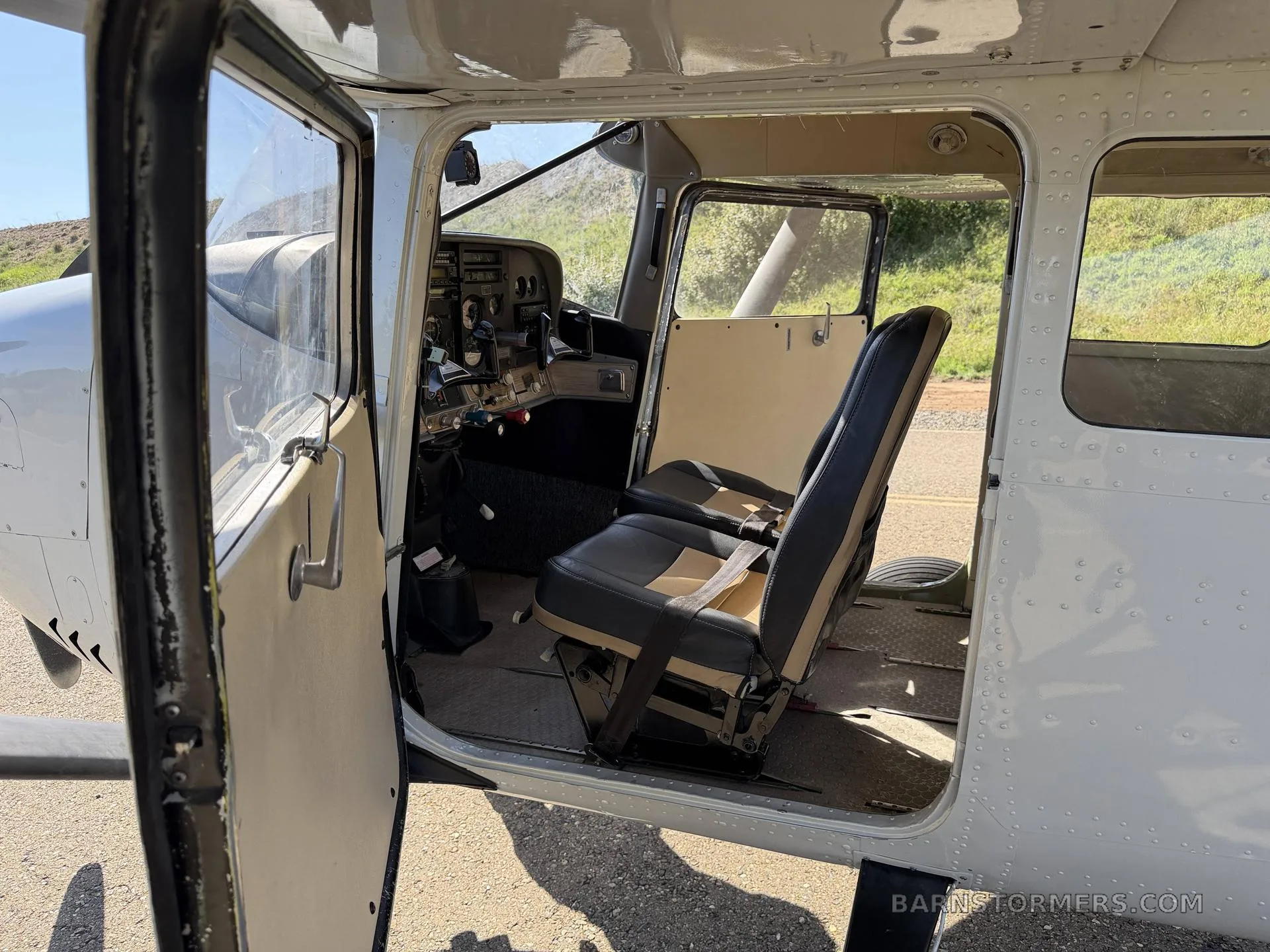 View into the open cabin door of a Cessna 206GT, showing the front two-tone seats and a glimpse of the cockpit.