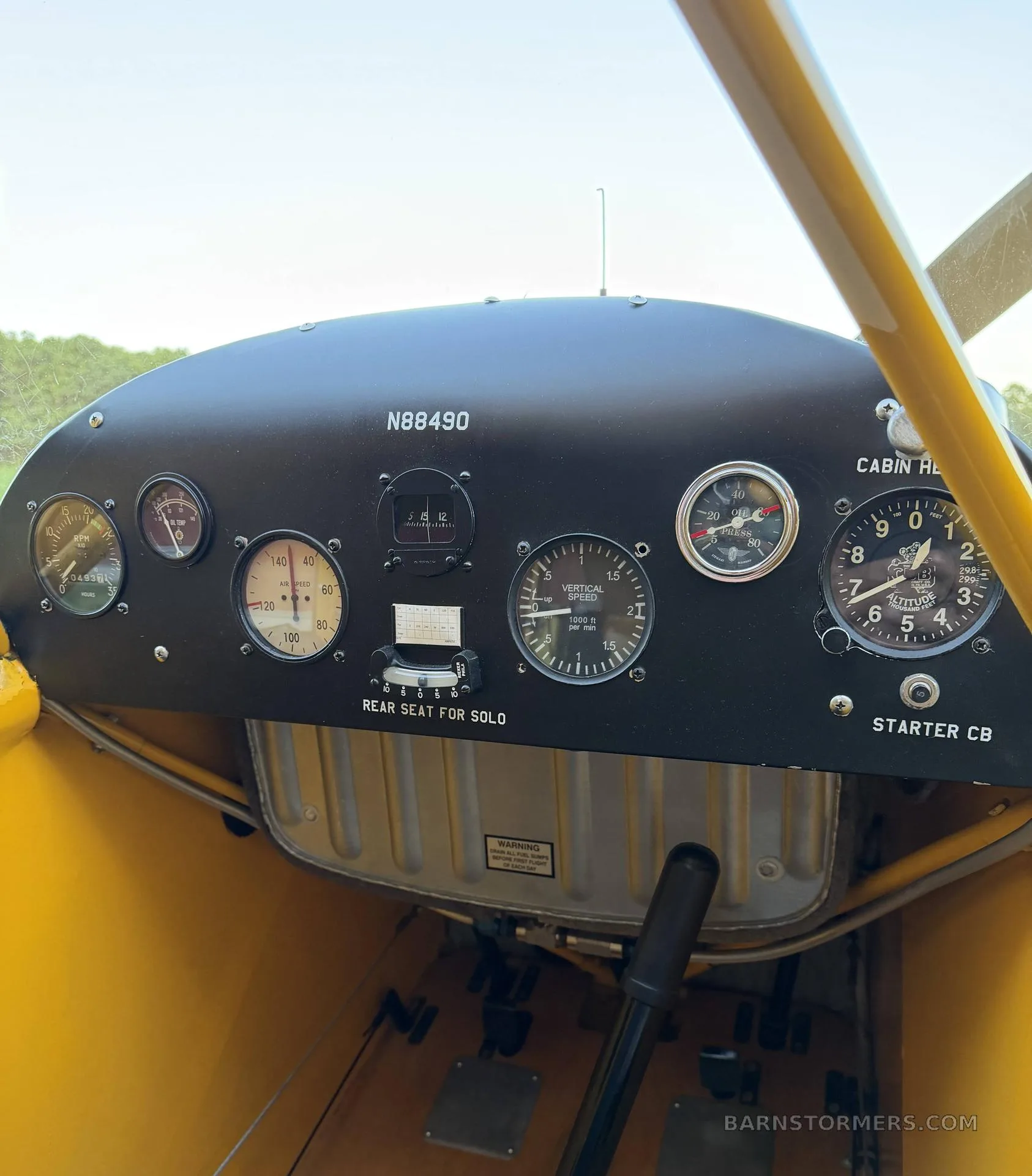 The black instrument panel of a yellow Piper Cub shows various gauges and controls, with "N88490" visible.
